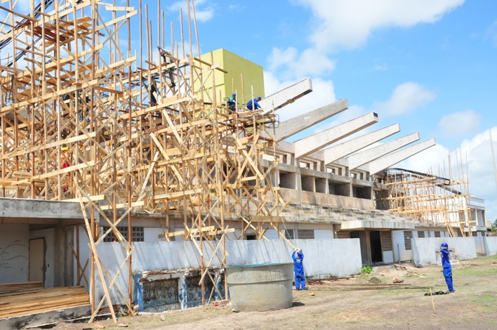 Operários trabalham na colocação de estrutura de concreto na cobertura
